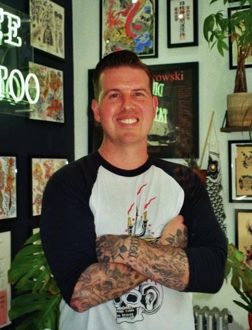 Mike Stapleton, arms crossed, in front of a wall of flash